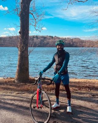 Man standing with a bike in front of a body of water