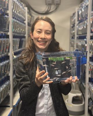 Smiling Woman with long hair holding a small tank with zebrafish
